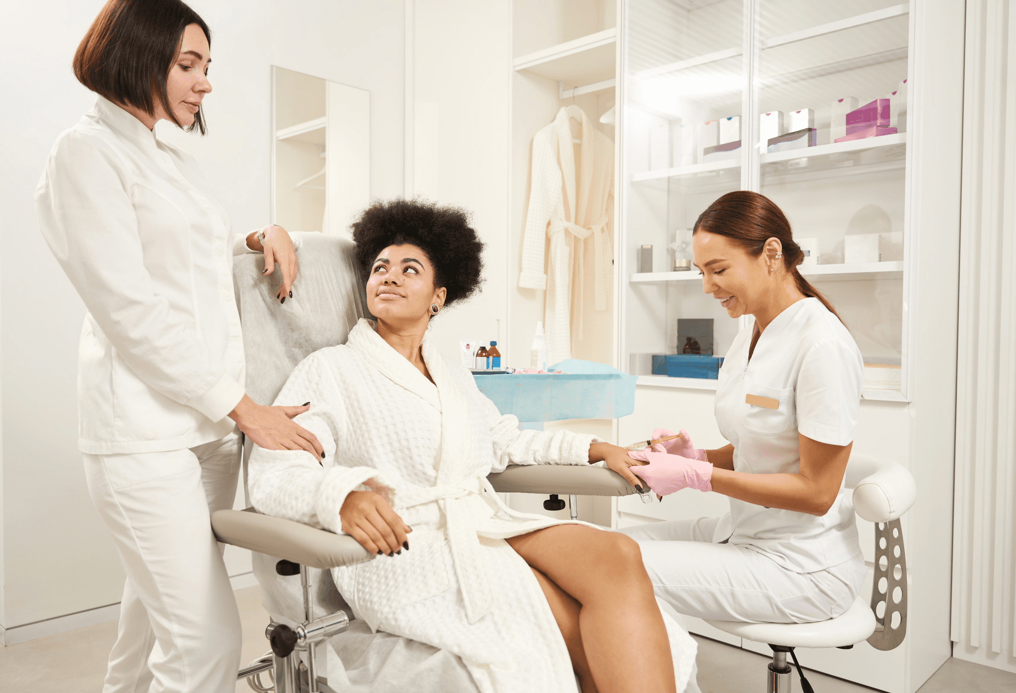 Beauty clinic treatment room with therapists and a client